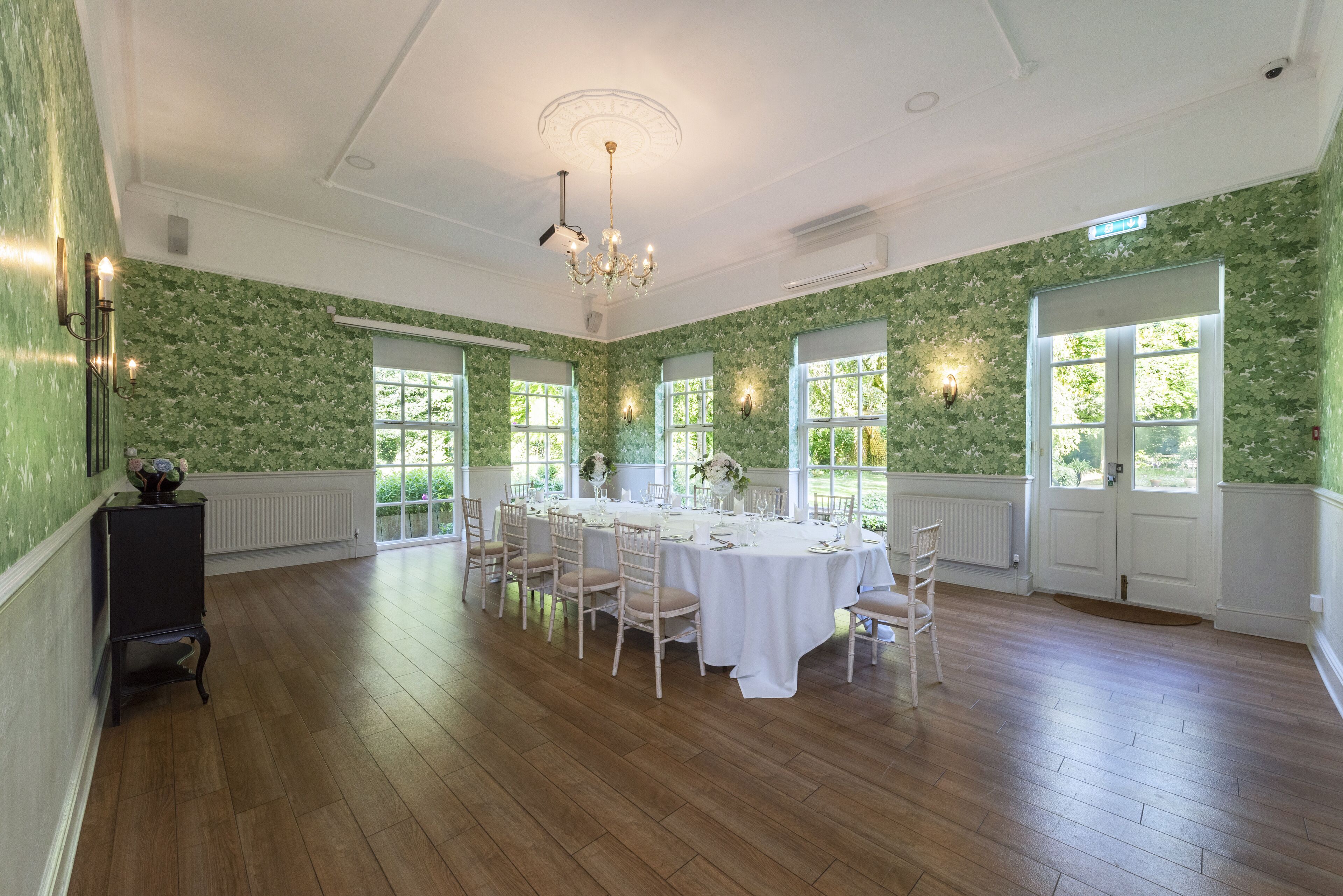 A dining room with a round table set for six, surrounded by chairs.