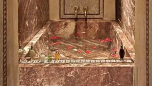 A marble bathroom with a bathtub, two faucets, and a decorative mirror. - Riad Mumtaz Mahal (Essaouira)