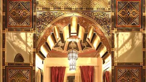 A room with a patterned floor, a bed with a red bedspread, and ornate wall decorations. - Riad Mumtaz Mahal (Essaouira)