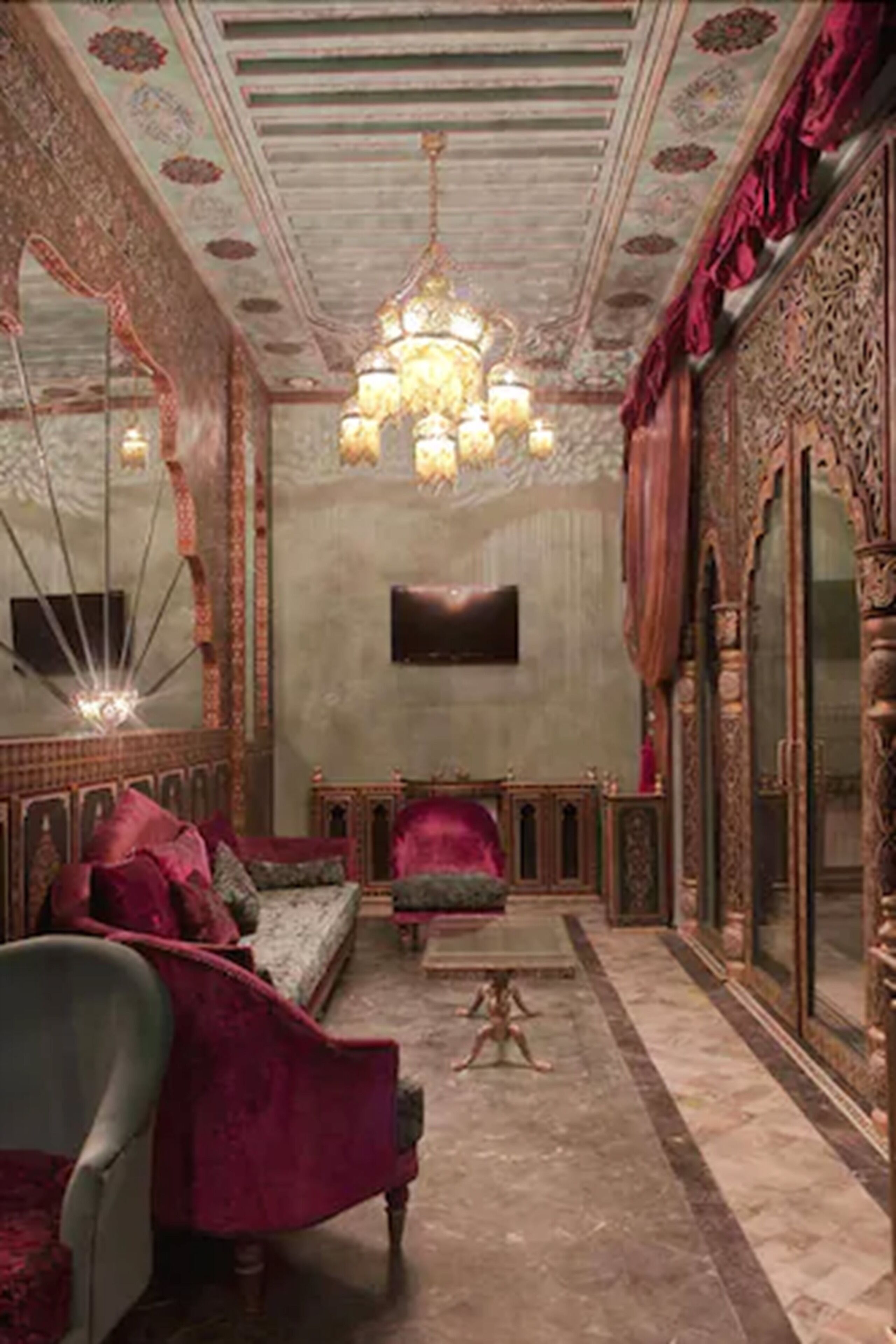 A room with a large ornate bed, a chandelier, and a mirror with intricate designs.