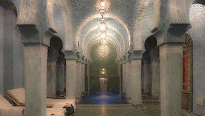 A corridor with a blue carpet, white beds, and ornate columns. - Riad Mumtaz Mahal (Essaouira)
