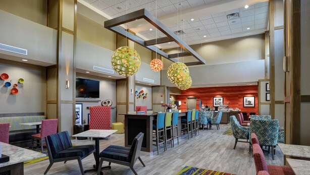 A modern hotel lobby with a bar area, seating arrangements, and decorative elements. - Hampton Inn & Suites Ardmore (Ardmore)