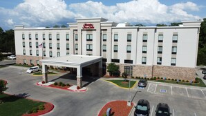 A Hampton Inn & Suites with a covered entrance, parking lot, and a flag.