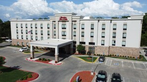 A Hampton Inn & Suites with a covered entrance, parking lot, and a flag.