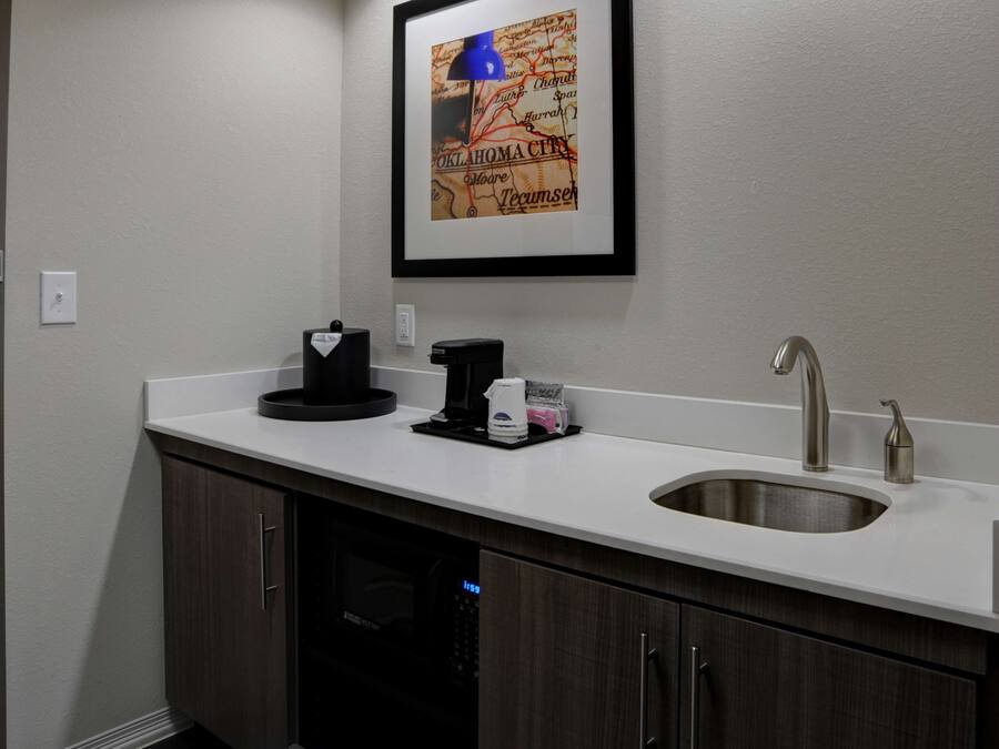 A modern kitchen with a white countertop, stainless steel sink, and dark wood cabinets.