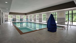 An indoor swimming pool with clear windows, a covered bench, and a safety sign. - Hampton Inn & Suites Ardmore (Ardmore)