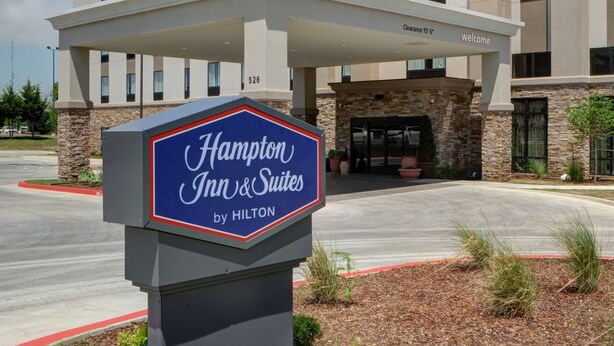 A Hampton Inn & Suites by Hilton building with a clear sky.