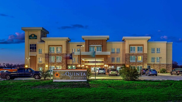A hotel with a sign reading "La Quinta by Wyndham" and a parking lot with cars. - La Quinta Inn & Suites by Wyndham Luling (Luling)