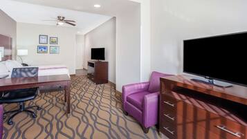 Habitación de hotel con cama, escritorio, silla, televisor y alfombra estampada.