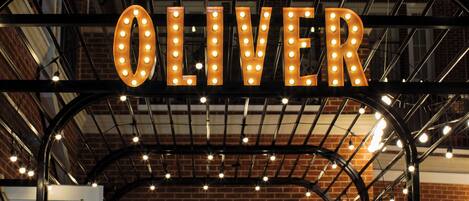 A building with a sign that reads "OLIVER" illuminated by lights.