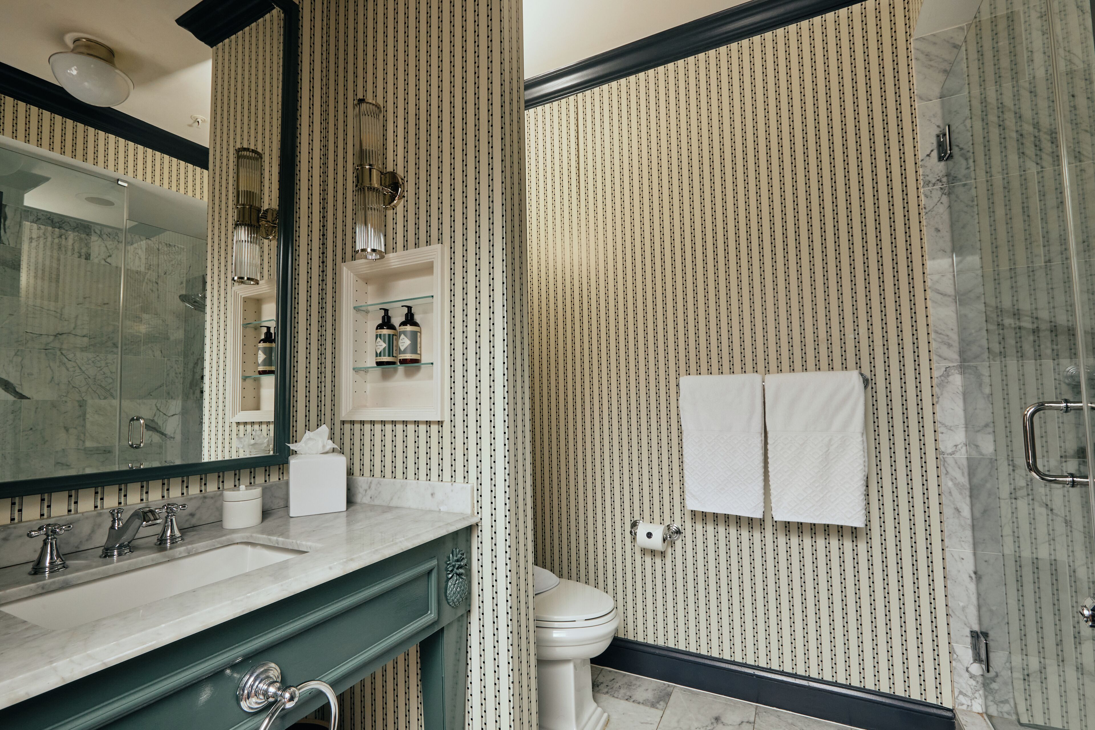 Un baño con un espejo grande, un lavabo, un inodoro y una zona de ducha.