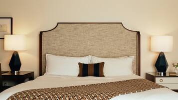 A neatly made bed with a patterned throw, two bedside lamps, and a framed picture on the nightstand.