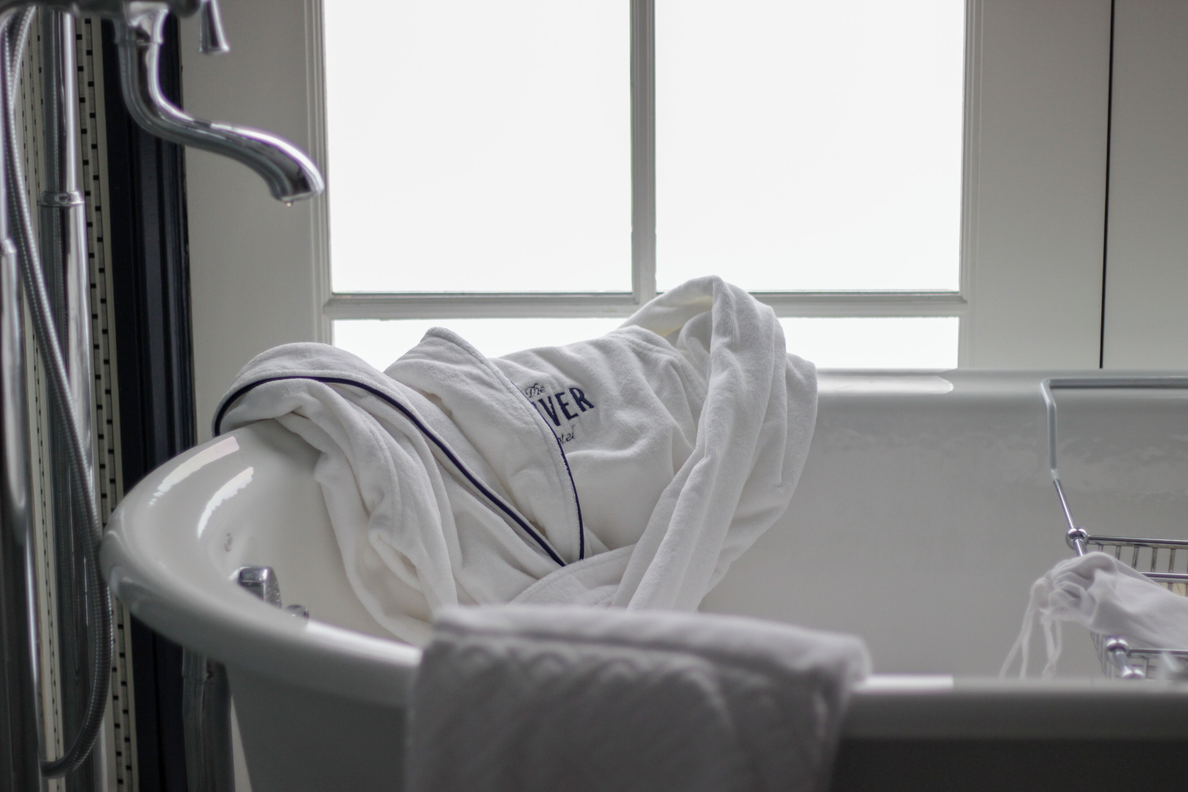 A bathroom with a white sink, a towel rack, and a window.