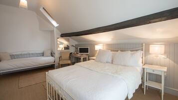 Een slaapkamer met een groot bed, een kleiner bed, een bureau en een stoel.