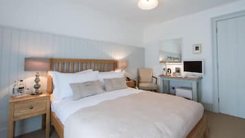 A neatly arranged bedroom with a large bed, bedside tables, a desk, and a chair.