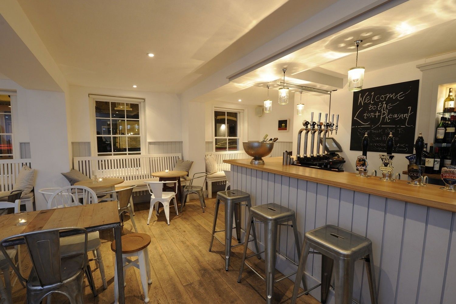 A cozy bar area with stools, a wooden counter, and a chalkboard sign.
