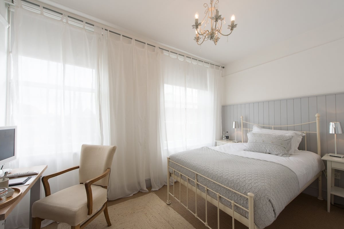 Un dormitorio con cama, una silla, un escritorio y una mesita de noche.
