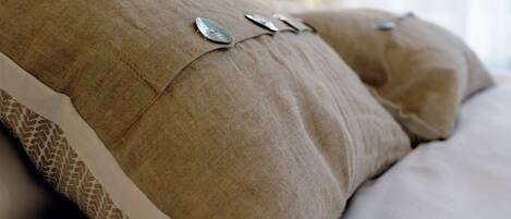 A close-up of a beige upholstered sofa with a patterned edge and two metallic buttons.