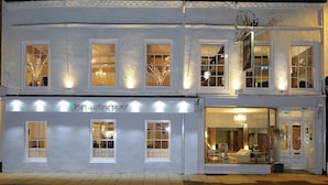 A two-story building with multiple windows, some with curtains, and a visible storefront with a sign. - Lion and Pheasant Hotel (Shrewsbury)