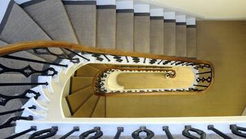 A spiral staircase with a wooden handrail and black balusters.