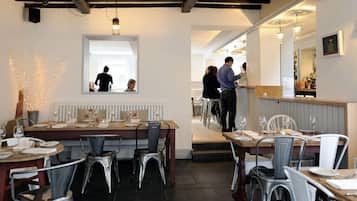 A restaurant interior with tables set for dining, a bar area, and a counter where staff are serving.
