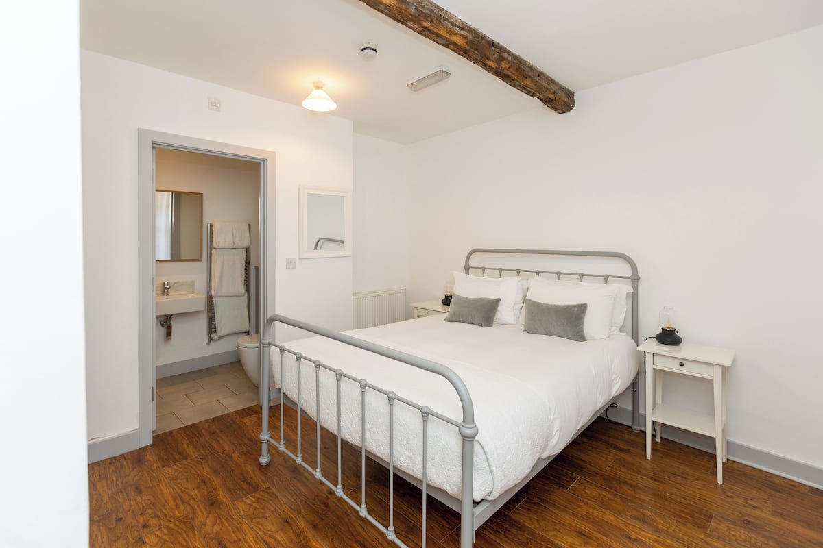 Un dormitorio con estructura de cama de metal, una mesita de noche y suelo de madera.