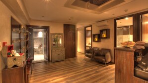 A spacious living room with a wooden floor, a leather sofa, a wooden cabinet, and a dining area with a pizza. - The Fourteen Luxury Boutique Hotel & Spa (Casablanca)