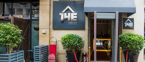 The entrance of The Fourteen Boutique Hotel & Spa, featuring a modern facade, a red carpet, and potted plants.