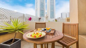 A balcony with a round wooden table, two wooden chairs, a potted plant, and a tray with breakfast items including fruit and a glass of orange juice. - The Fourteen Luxury Boutique Hotel & Spa (Casablanca)