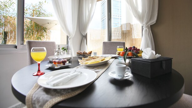 A breakfast table set with plates, a glass of orange juice, a fruit bowl, and a box of tissues. - The Fourteen Luxury Boutique Hotel & Spa (Casablanca)