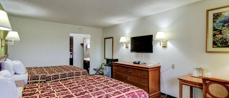 A hotel room with two beds, a television, a dresser, and a desk with a chair.