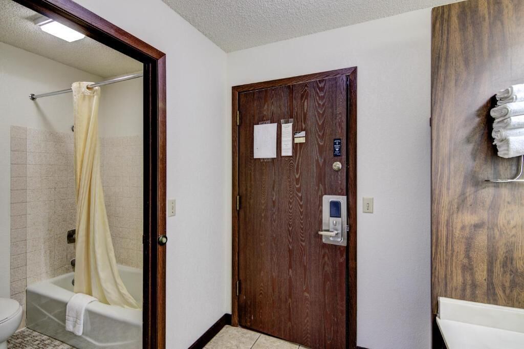 Een badkamer met een douche, toilet en een houten deur met een handdoekhouder.
