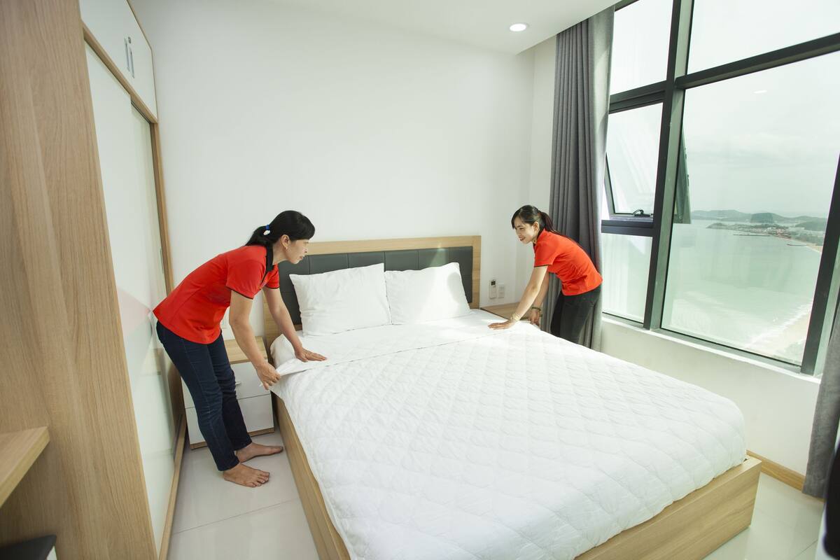 A neatly made bed in a modern hotel room with a large window offering a view of the cityscape.