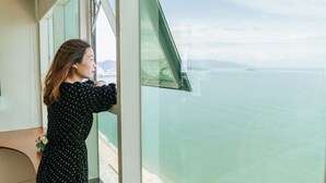 A person standing by a window with a view of the sea. - Beach Front Apartment (Nha Trang)