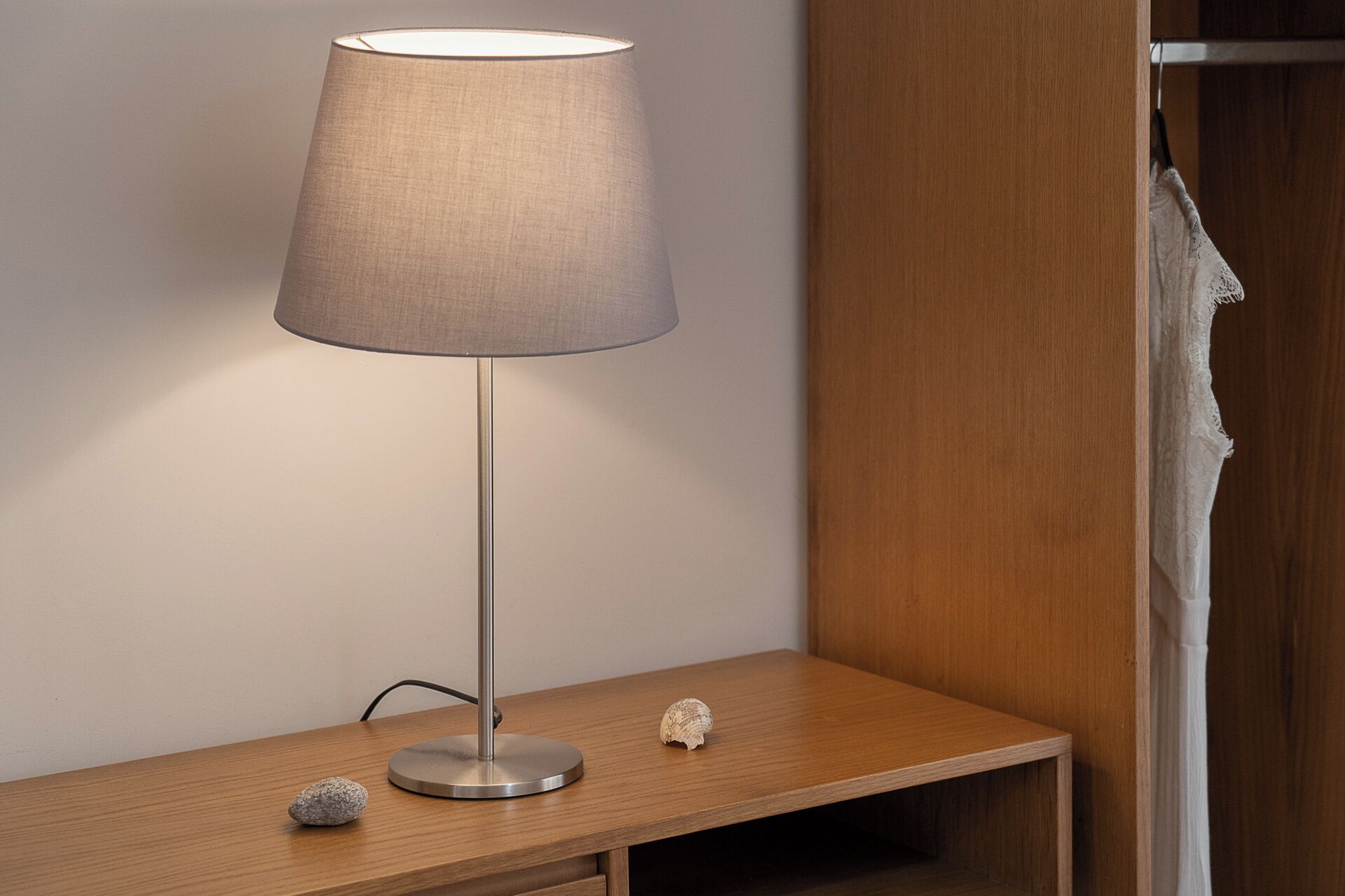 En moderne gulvlampe med en cylinderformet skærm på et trænatbord.