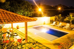 A swimming pool with a tiled deck, surrounded by lounge chairs and potted plants. - Pousada Bemtevi em Búzios (Búzios)