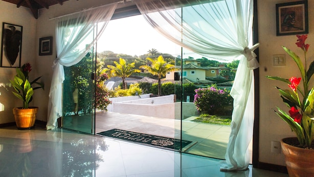 L’entrée d’un hôtel avec une porte en verre, des rideaux blancs et des plantes en pot.