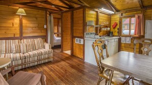 A cozy cabin interior with a wooden interior, a sofa, a dining table, and a kitchenette.