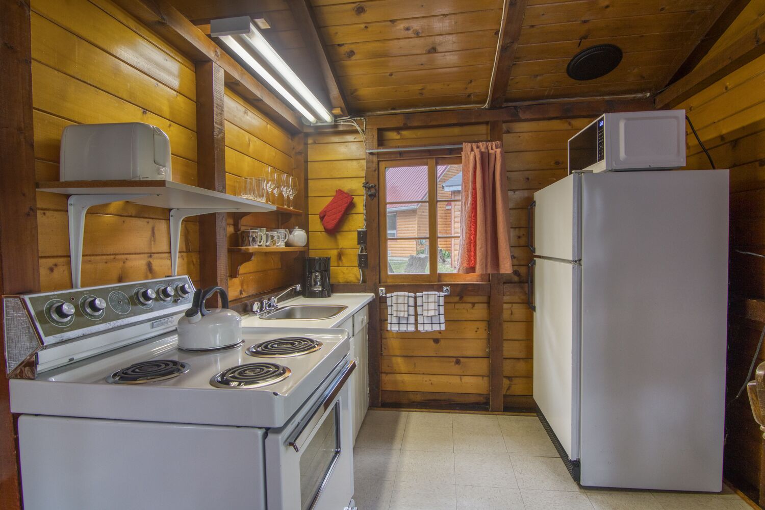 A compact kitchen with a stove, sink, and refrigerator.