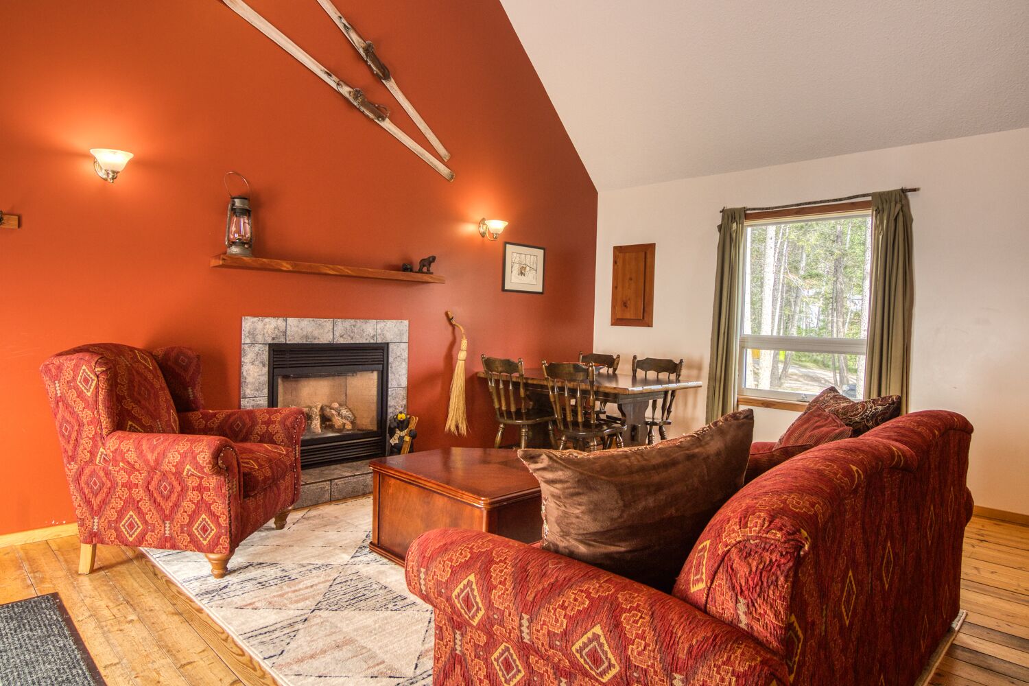Una sala de estar acogedora con chimenea, muebles de diseño rojo y una mesa de comedor con sillas.