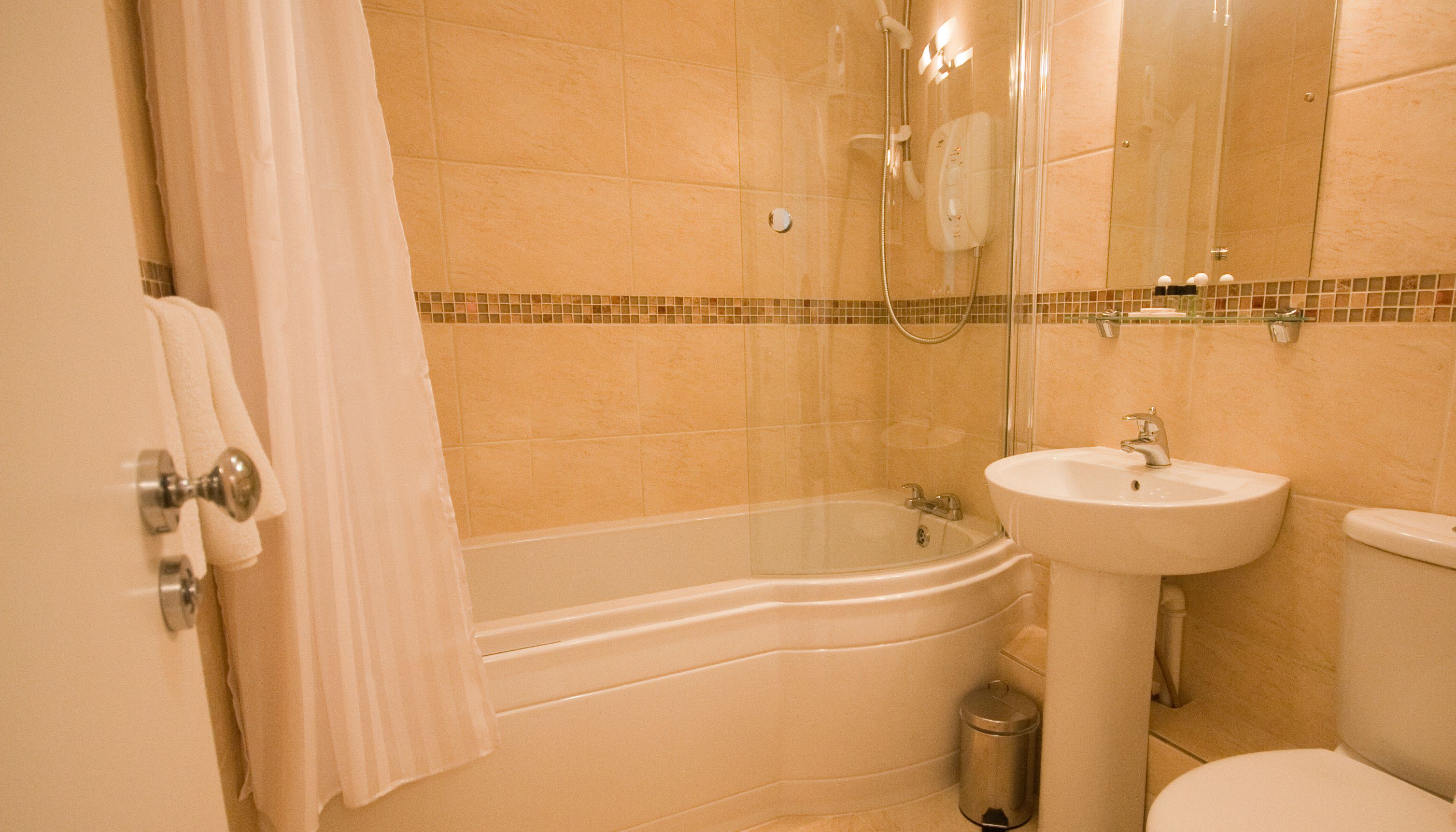 A bathroom with a bathtub, sink, toilet, and a glass shower enclosure.
