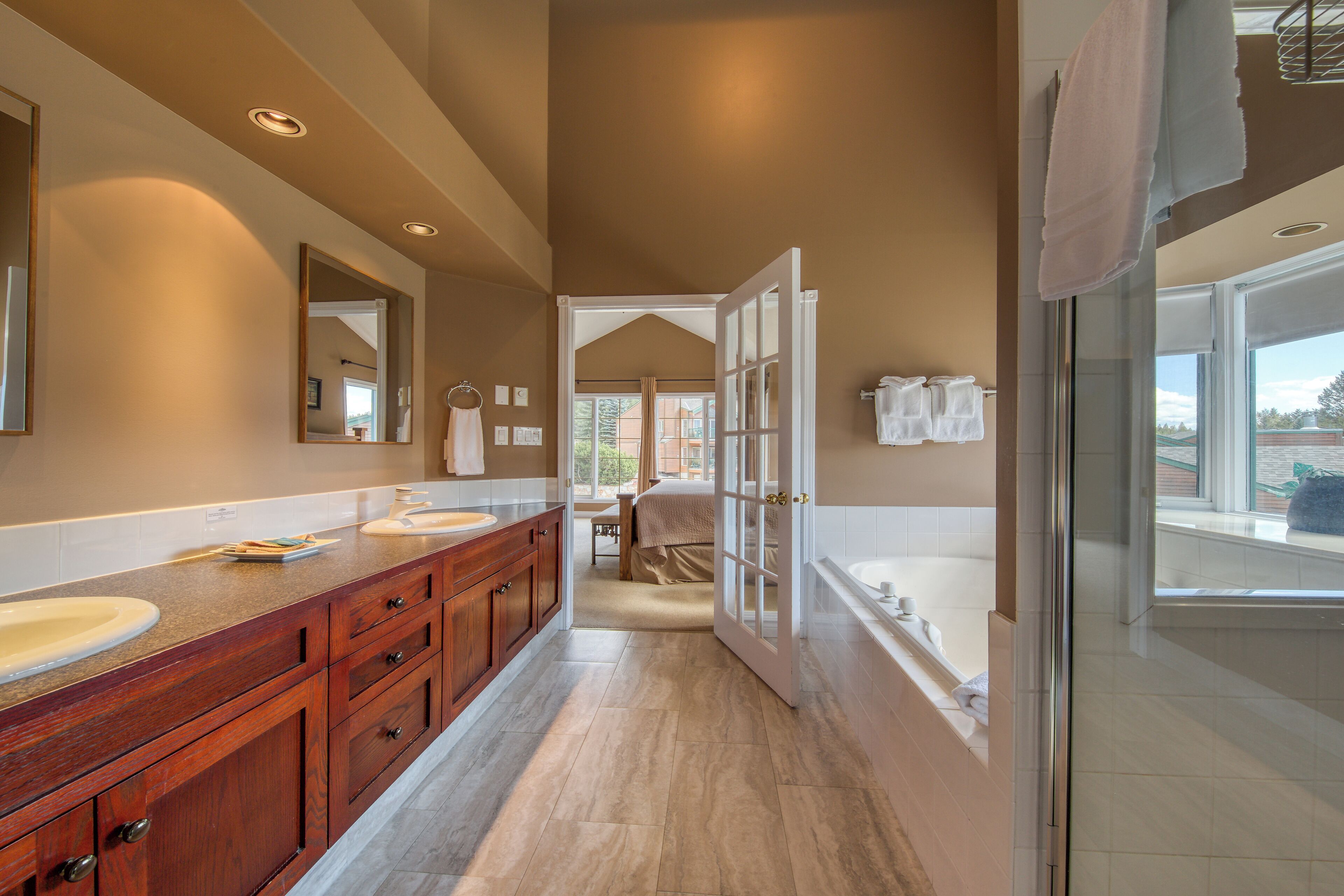 Une salle de bain moderne dotée d’un grand meuble-lavabo, d’une douche à parois de verre et offrant une vue sur l’extérieur.
