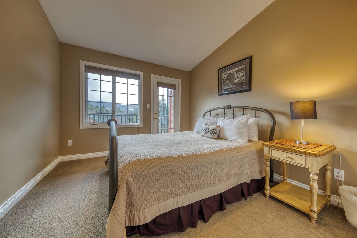 A bedroom with a bed, bedside table, lamp, and a window.