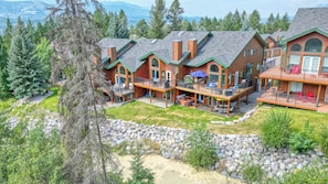 A multi-story lodge with outdoor decks and a stone retaining wall.