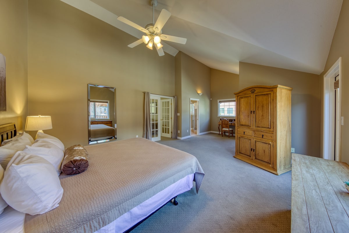 A spacious bedroom with a large bed, a ceiling fan, and a wooden cabinet.
