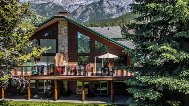 A lodge with a stone facade, large windows, and a deck with outdoor seating.