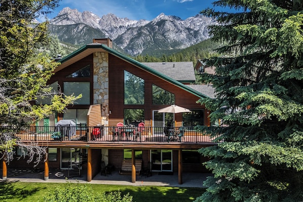 A lodge with a stone facade, large windows, and a deck with outdoor seating.