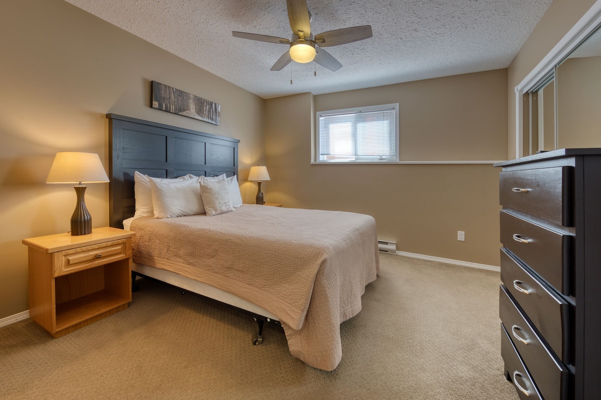 A bedroom with a bed, nightstands, a dresser, a ceiling fan, and a window.