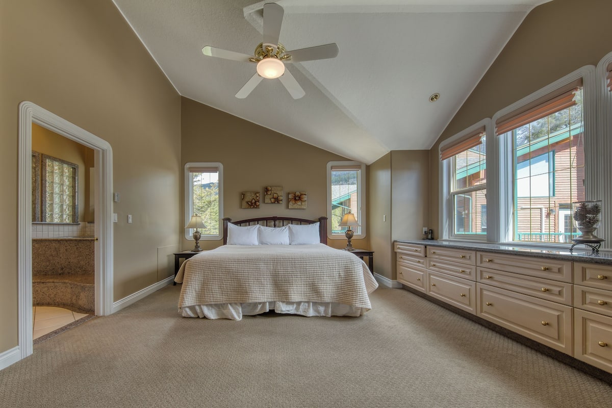 A bedroom with a bed, nightstands, a dresser, and a ceiling fan.