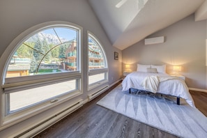 A bedroom with a large window, a bed, and a nightstand.